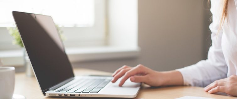 A woman's hands working on a laptop keyboard.