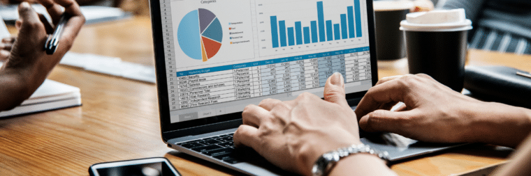 Hands are visible typing on a laptop, with the screen displaying the MPR logo, bar graphs, and a data table. A cup of coffee is situated next to the laptop.