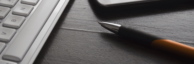 A close-up view of a pen, with a keyboard visible in the left corner.