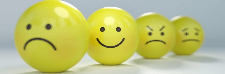 Four yellow balls with facial expressions depicting different emotions: a sad face, a happy face, an angry face, and a worried face.