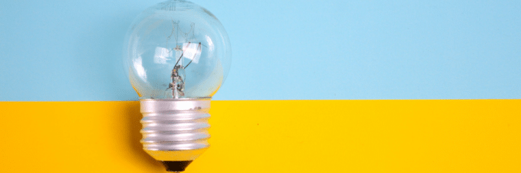 A close-up of a light bulb, with the background divided into two halves of blue and yellow